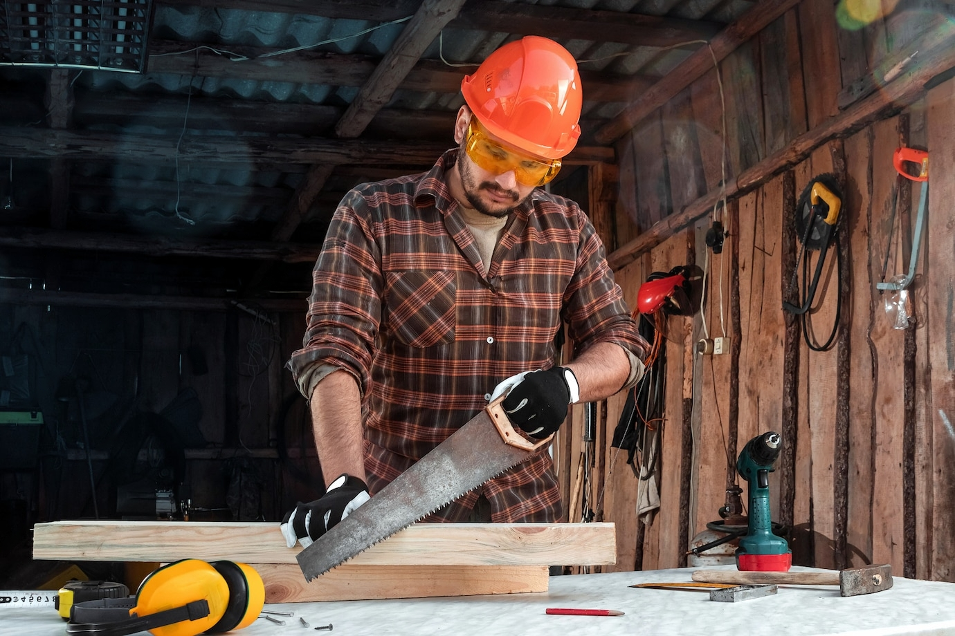 A man in safety gear working with a pipe in a workshop.